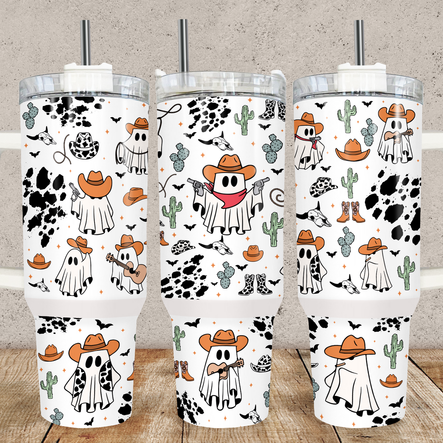 A set of three 40oz stainless steel tumblers with a white background and a pattern of illustrated ghosts, cacti, and cowboy hats.