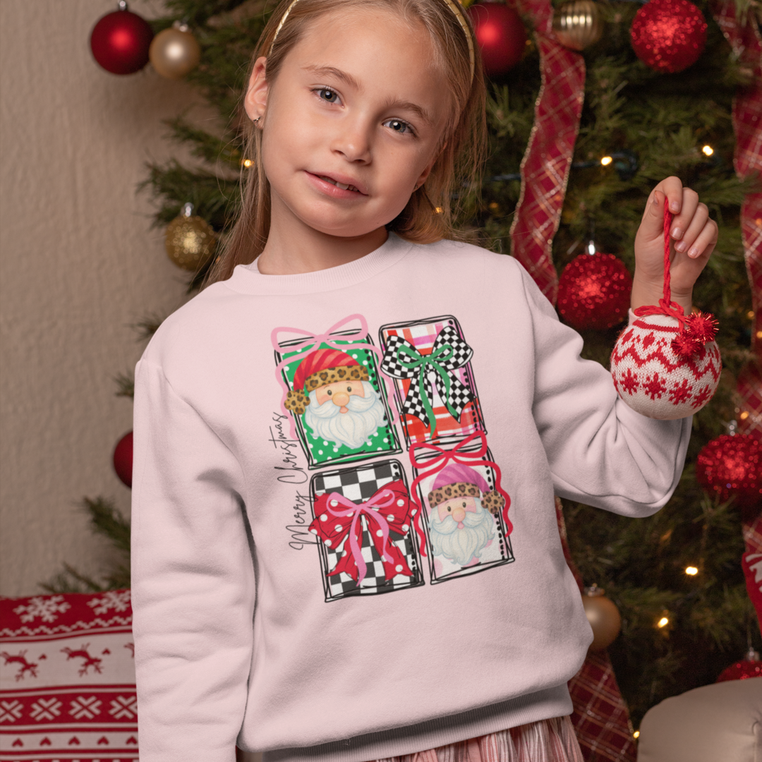 Young girl wearing a pink Christmas-themed sweatshirt in front of a decorated tree.