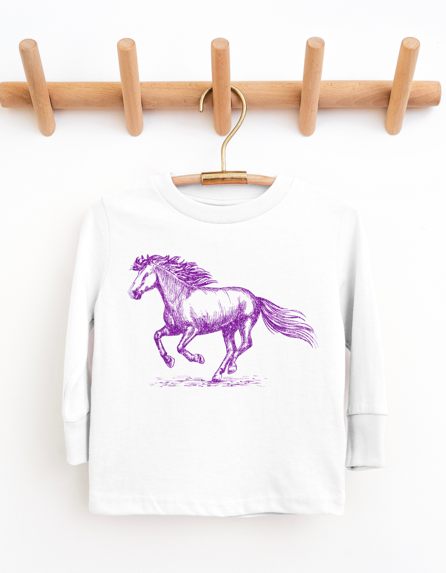 White long-sleeve shirt with a purple horse graphic on a wooden hanger against a white background