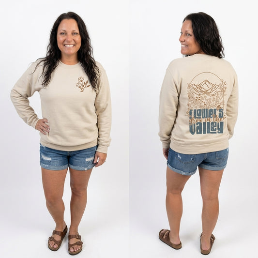Woman wearing a beige sweatshirt with a design on the front and back, standing against a white background.