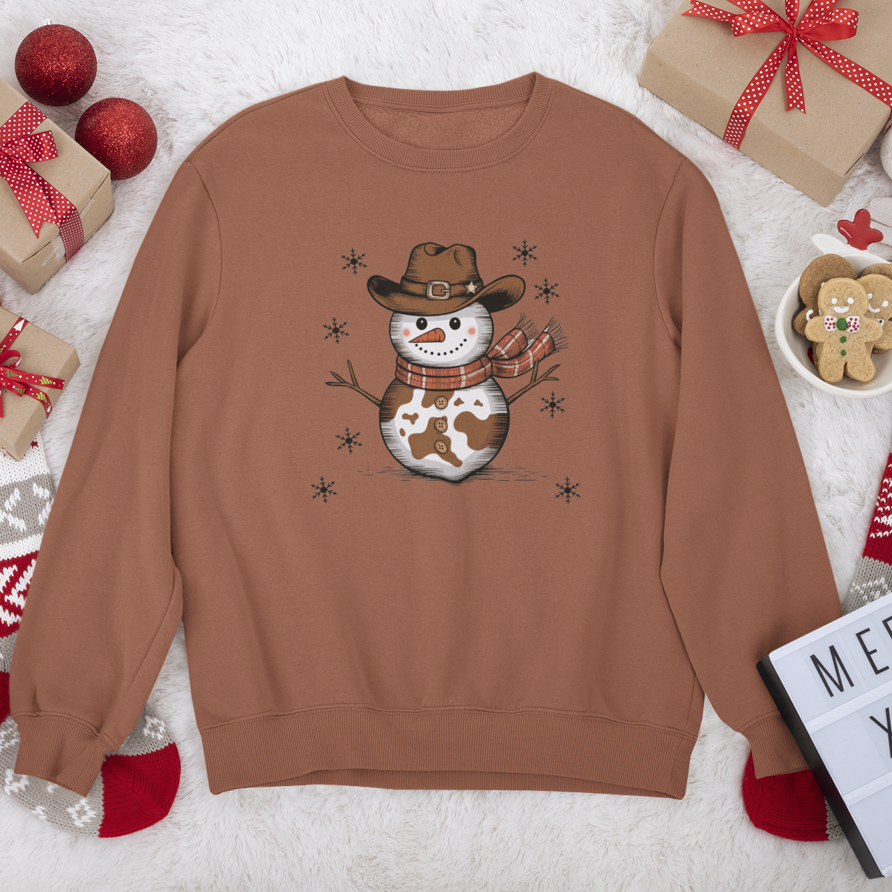 Brown sweatshirt with a snowman design on a festive background with Christmas decorations.