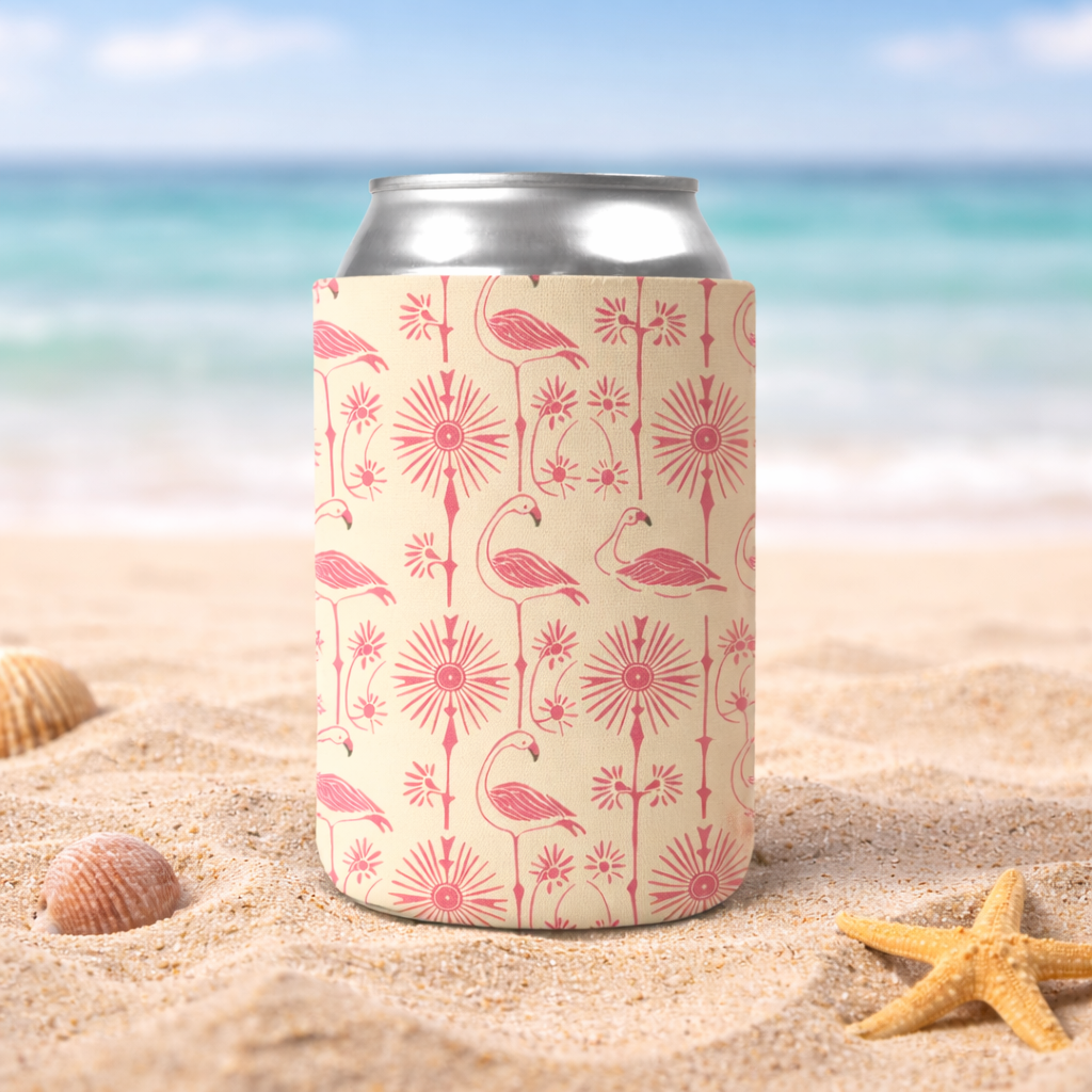 Can cooler with pink flamingo design on a sandy beach with ocean in the background