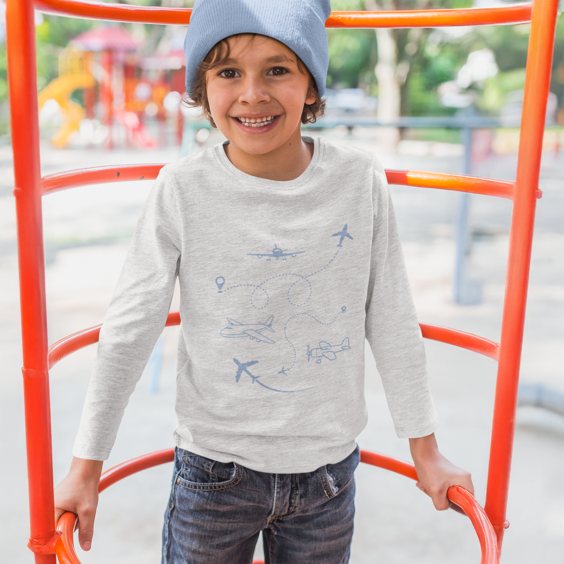 Child wearing a gray sweater with airplane patterns on a playground.