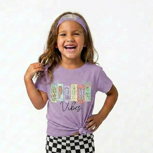 Child wearing a purple shirt with colorful text and checkered pants on a white background