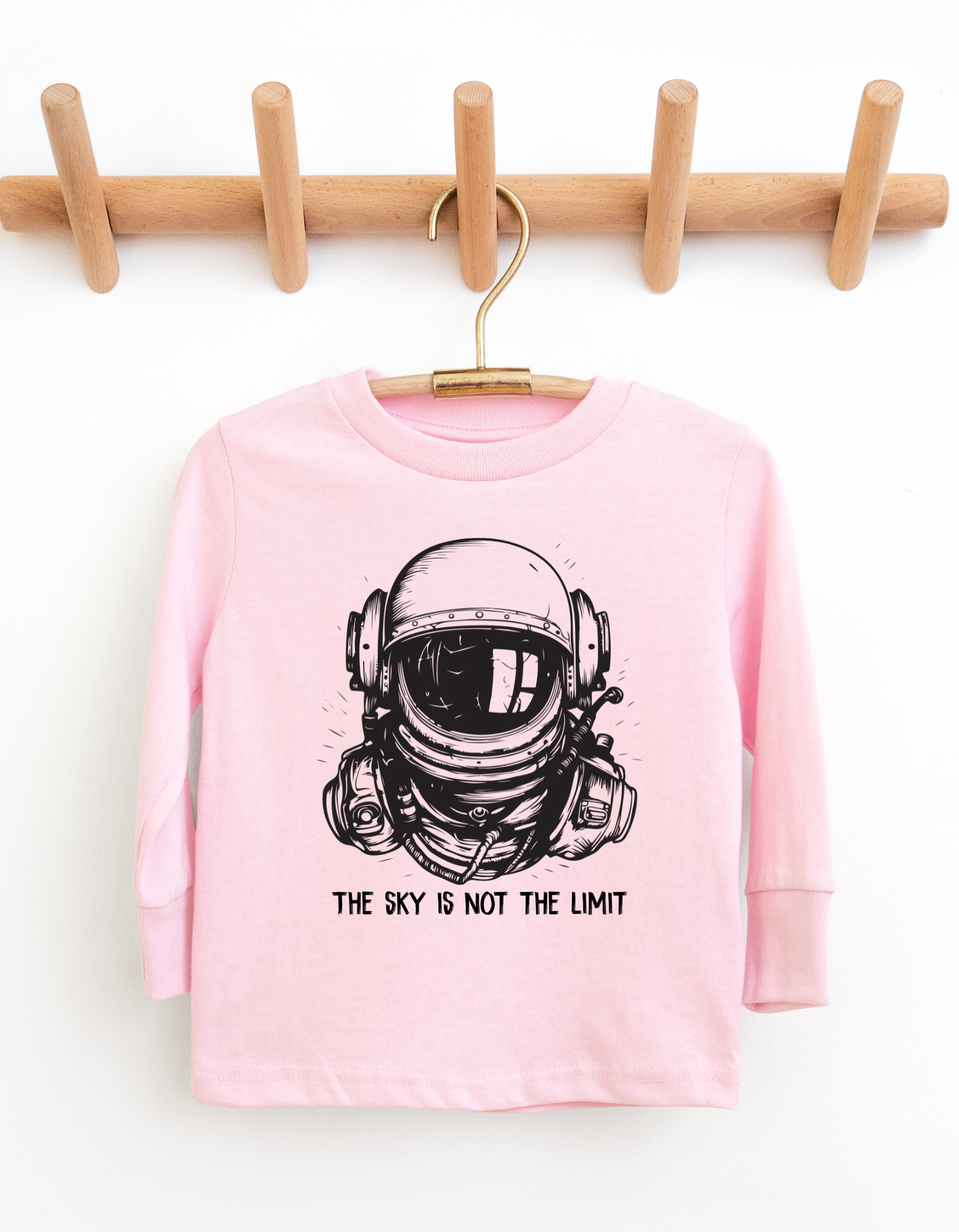 Pink long-sleeve shirt with an astronaut graphic and 'The sky is not the limit' text on a white background.