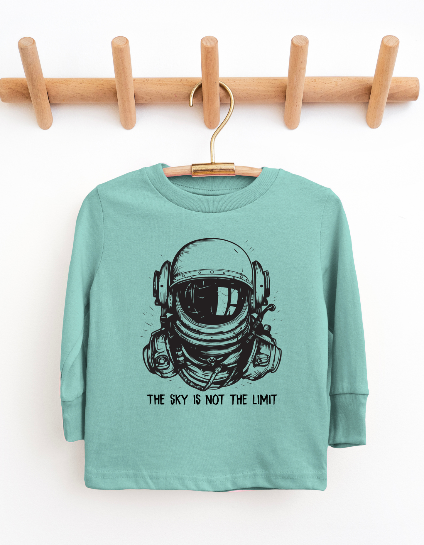 Teal long-sleeve shirt with astronaut graphic and 'The sky is not the limit' text on a white background.