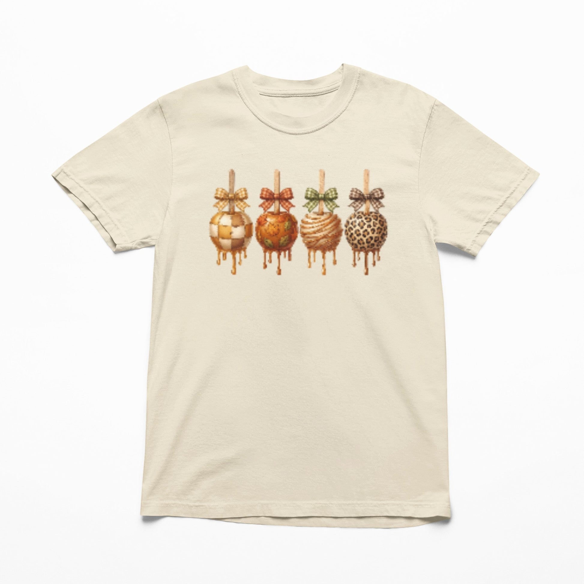 Tea-Shirt Shoppe cream youth graphic tee featuring four caramel apples with checkered, leopard, and autumn patterns.