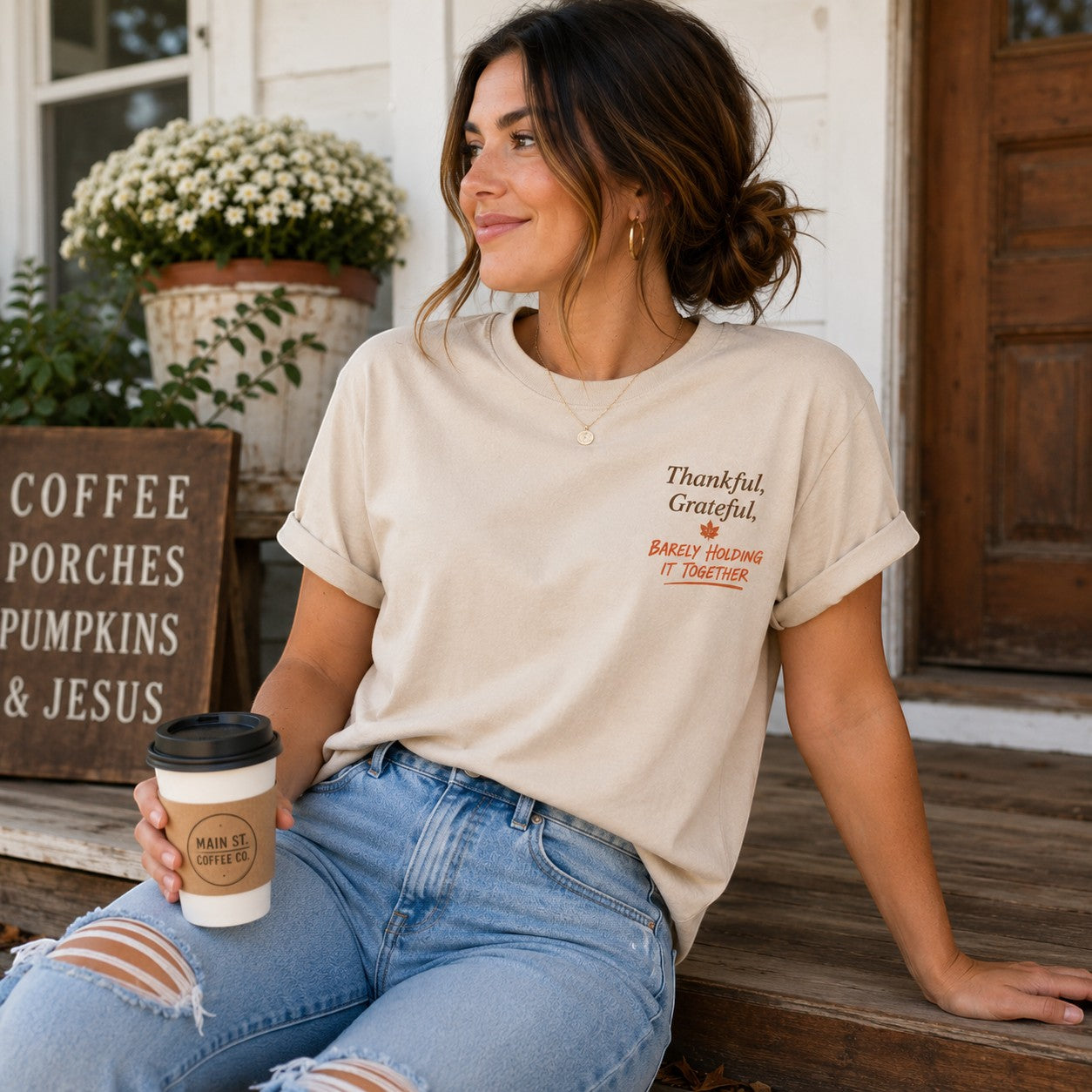 Tea Shirt Shoppe Wholesale beige graphic tee with Thankful Grateful text worn by a woman holding a coffee cup