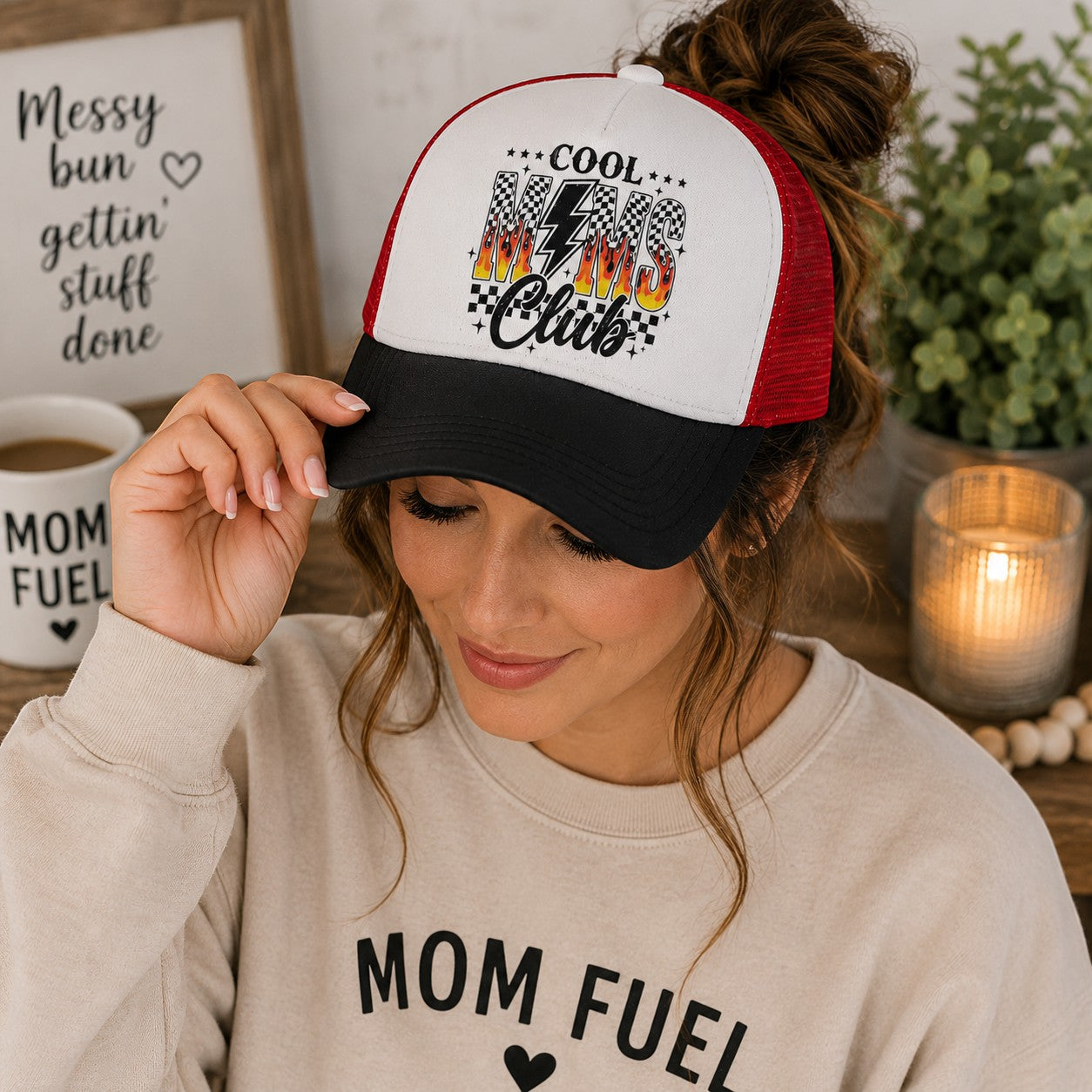 Tea Shirt Shoppe Wholesale trucker hat with white front panel, red mesh back, and black brim. Features "Cool Moms Club" graphic with flames and checkered flag.