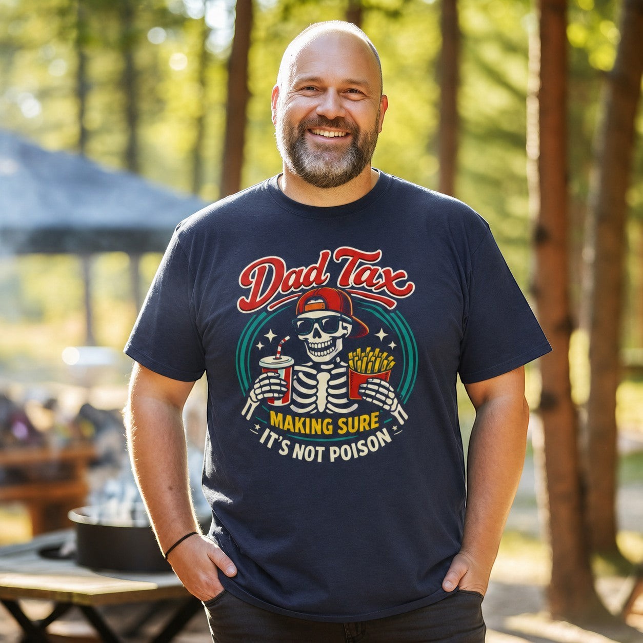 Tea Shirt Shoppe Wholesale navy blue cotton graphic tee with a skeleton wearing sunglasses and a red cap, holding fries and a drink. Text reads "Dad Tax: Making Sure It's Not Poison."