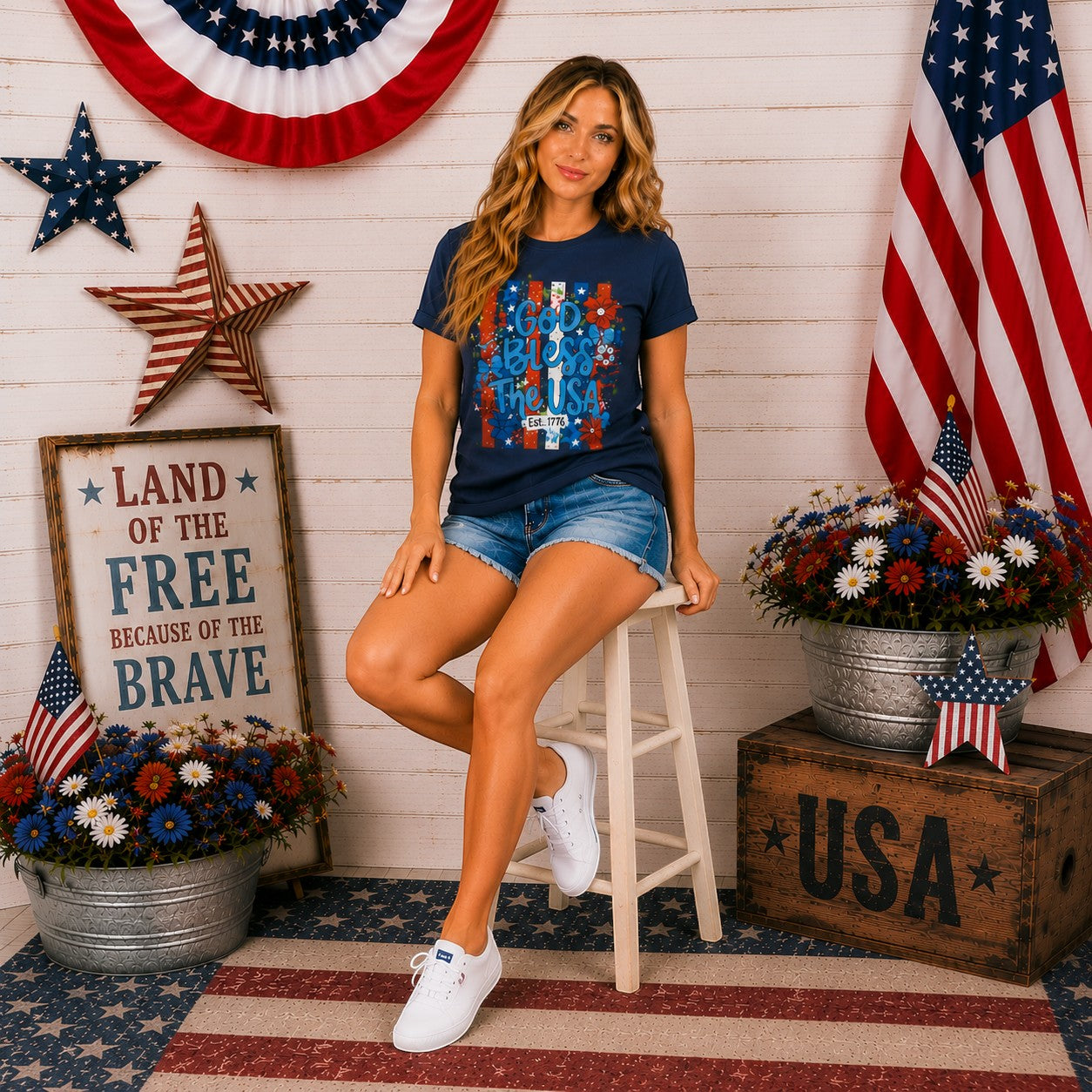 Tea Shirt Shoppe Wholesale navy graphic tee with "God Bless The USA" text and floral accents, Est. 1776 detail.