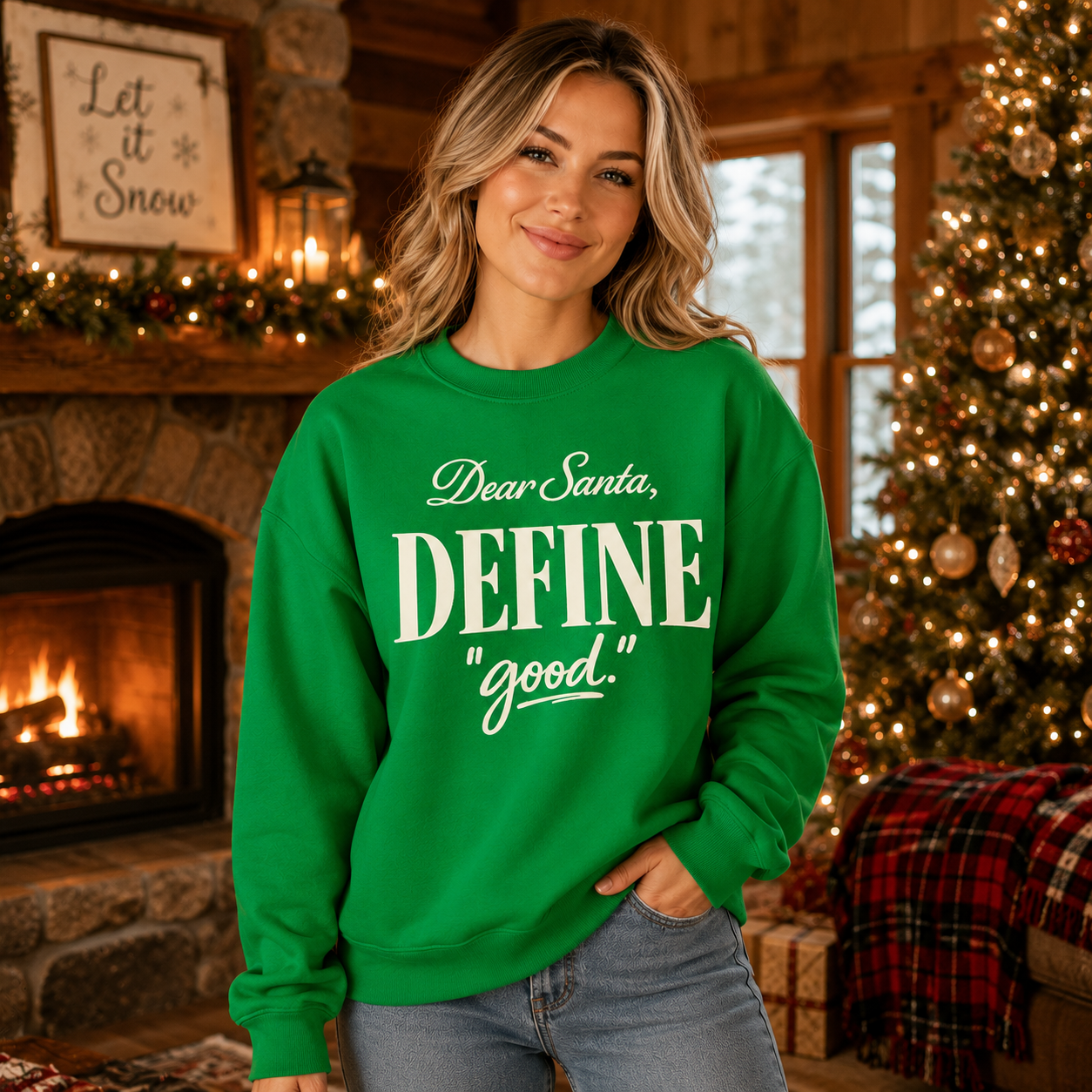Woman wearing a green Tea Shirt Shoppe Wholesale Christmas sweatshirt with Dear Santa Define Good text in a cozy room