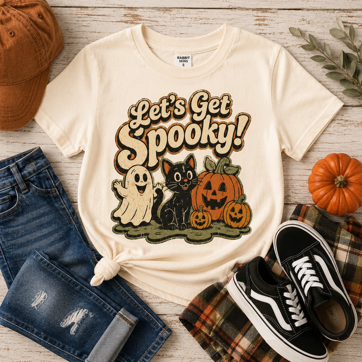 Tea Shirt Shoppe Wholesale cream graphic tee featuring a ghost, black cat, and pumpkins for Halloween
