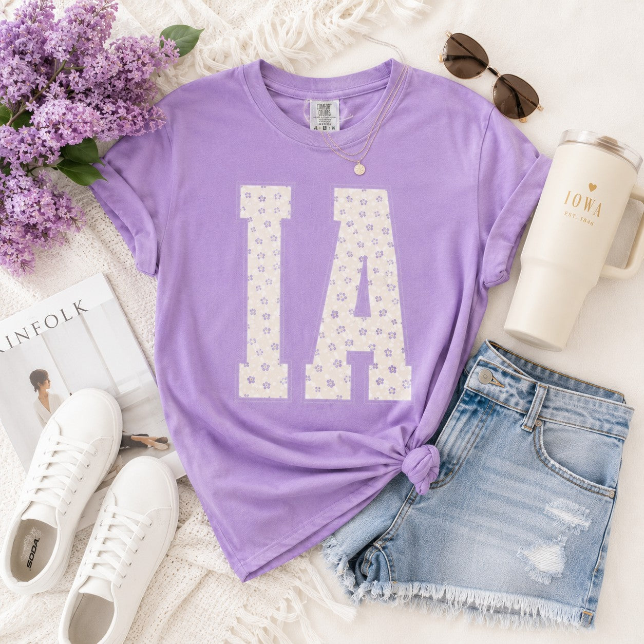 Tea Shirt Shoppe Wholesale lavender cotton graphic tee with floral IA varsity letters, styled with denim shorts.