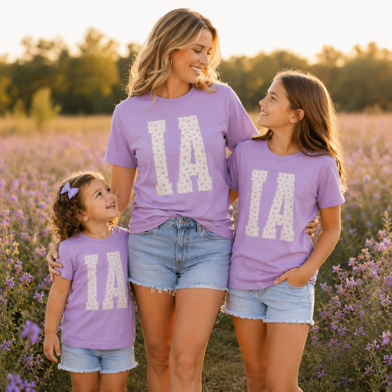 Tea Shirt Shoppe Wholesale lavender cotton graphic tees with floral IA print worn by a mother and two daughters.