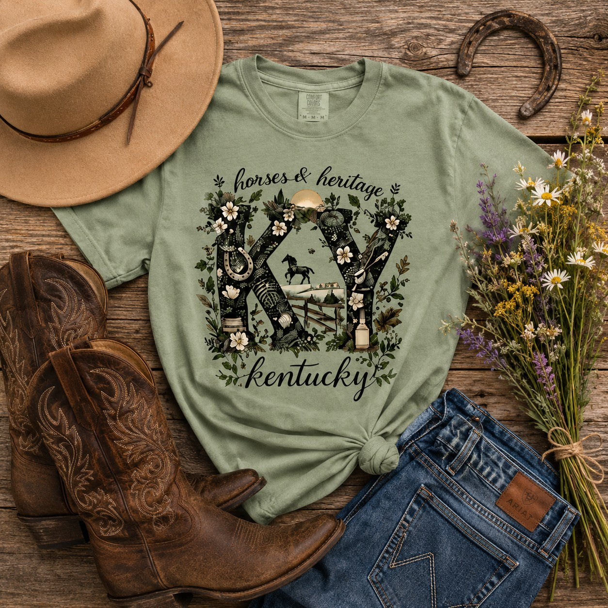 Tea Shirt Shoppe Wholesale sage green graphic tee featuring KY letters with horse, bourbon, and floral illustrations.