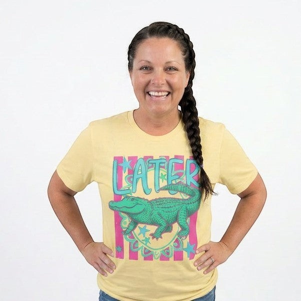 Tea Shirt Shoppe Wholesale yellow 100% cotton graphic tee with a green alligator and "LATER" text. Short sleeves, crew neck.