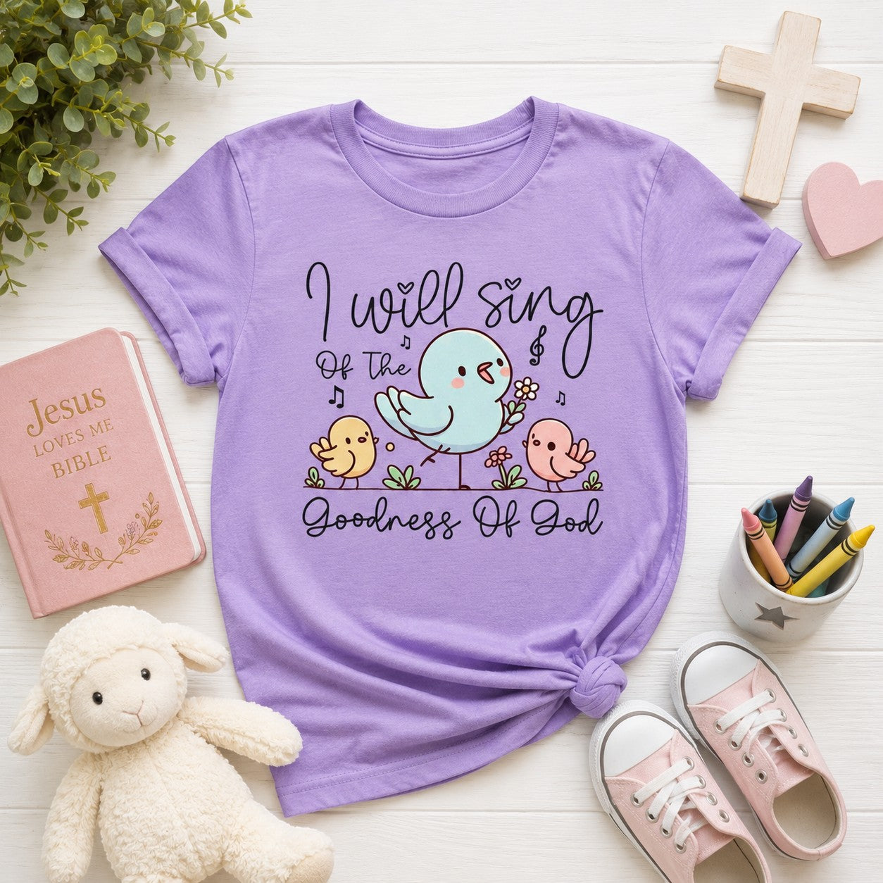 Tea Shirt Shoppe Wholesale lavender 100% cotton youth graphic tee with a blue bird, chicks, flowers, and musical notes. Reads "I will sing of the goodness of God."