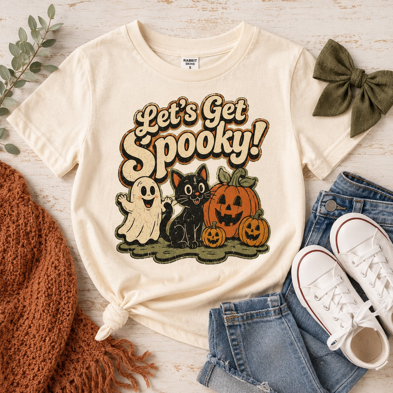 Tea Shirt Shoppe Wholesale cream graphic tee featuring a ghost, black cat, and pumpkins for Halloween.