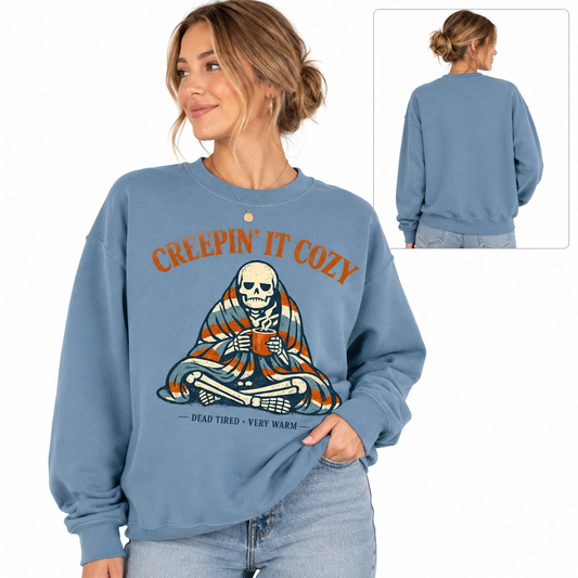Tea Shirt Shoppe Wholesale light slate graphic sweatshirt featuring a skeleton wrapped in a blanket drinking coffee
