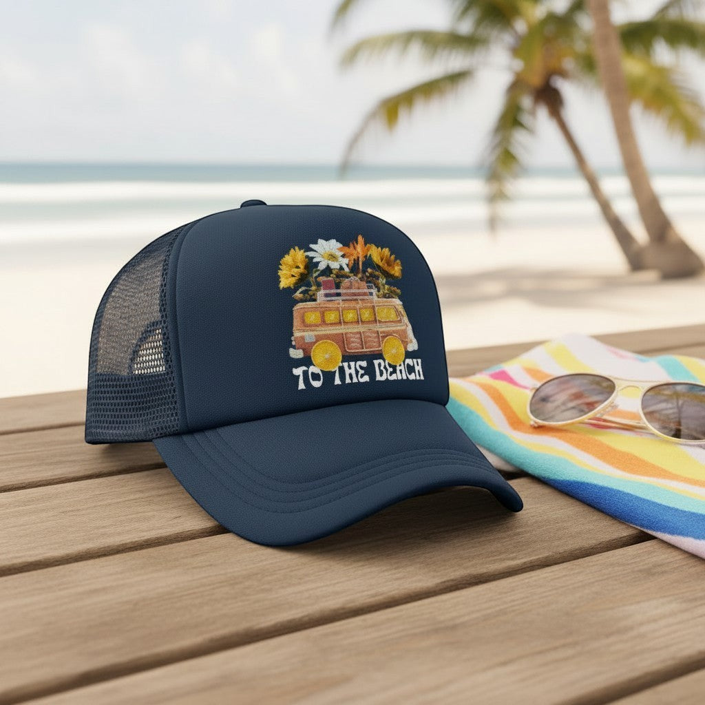 Tea Shirt Shoppe Wholesale navy blue trucker hat with a graphic of a vintage van loaded with flowers and the text "TO THE BEACH".