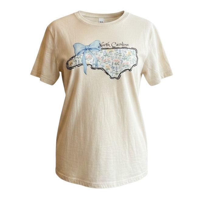 Tea Shirt Shoppe Wholesale cream graphic t-shirt with North Carolina outline filled with floral pattern and blue bow.