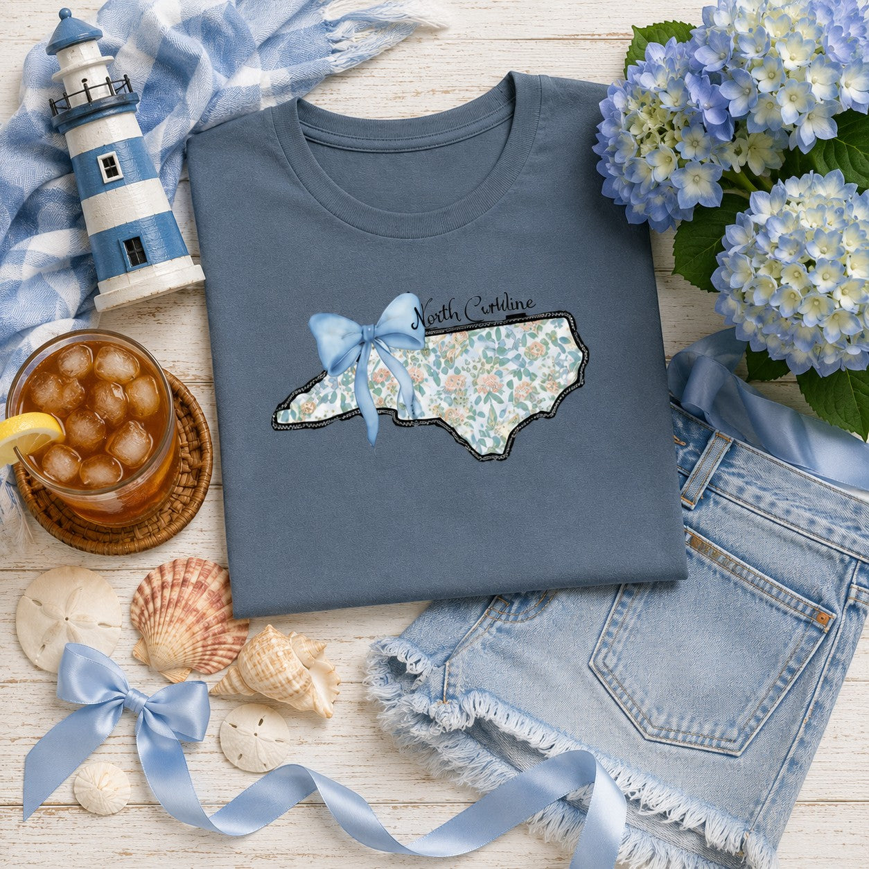Tea Shirt Shoppe Wholesale blue graphic tee featuring a North Carolina state outline with floral print and a blue bow.