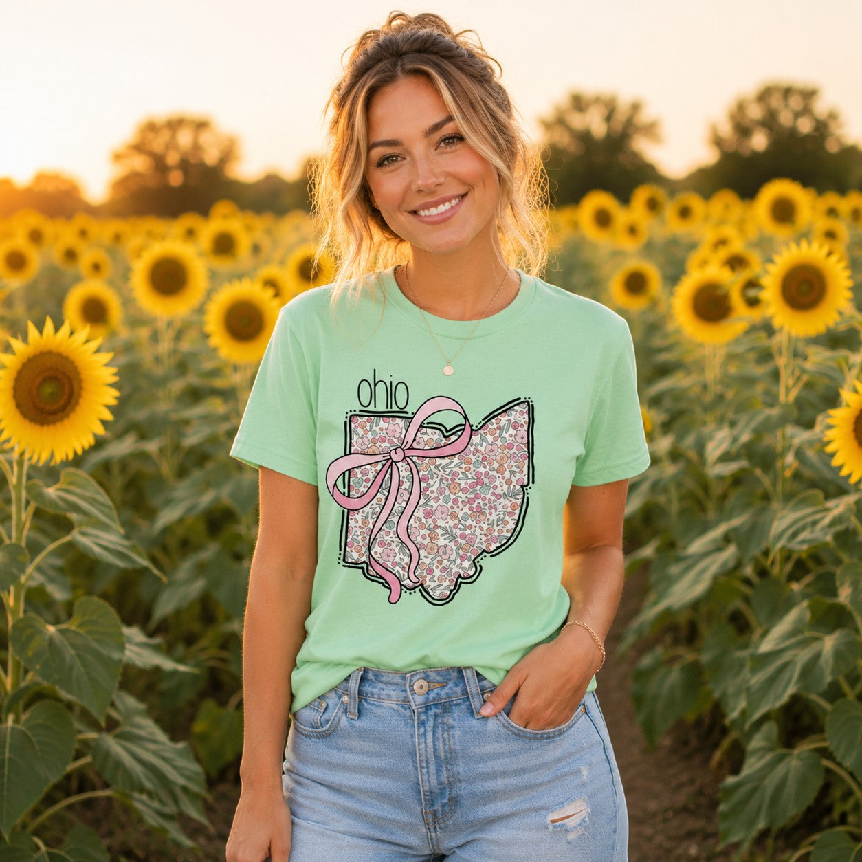 Tea Shirt Shoppe Wholesale mint green cotton graphic tee with floral Ohio state outline and pink bow in sunflower field