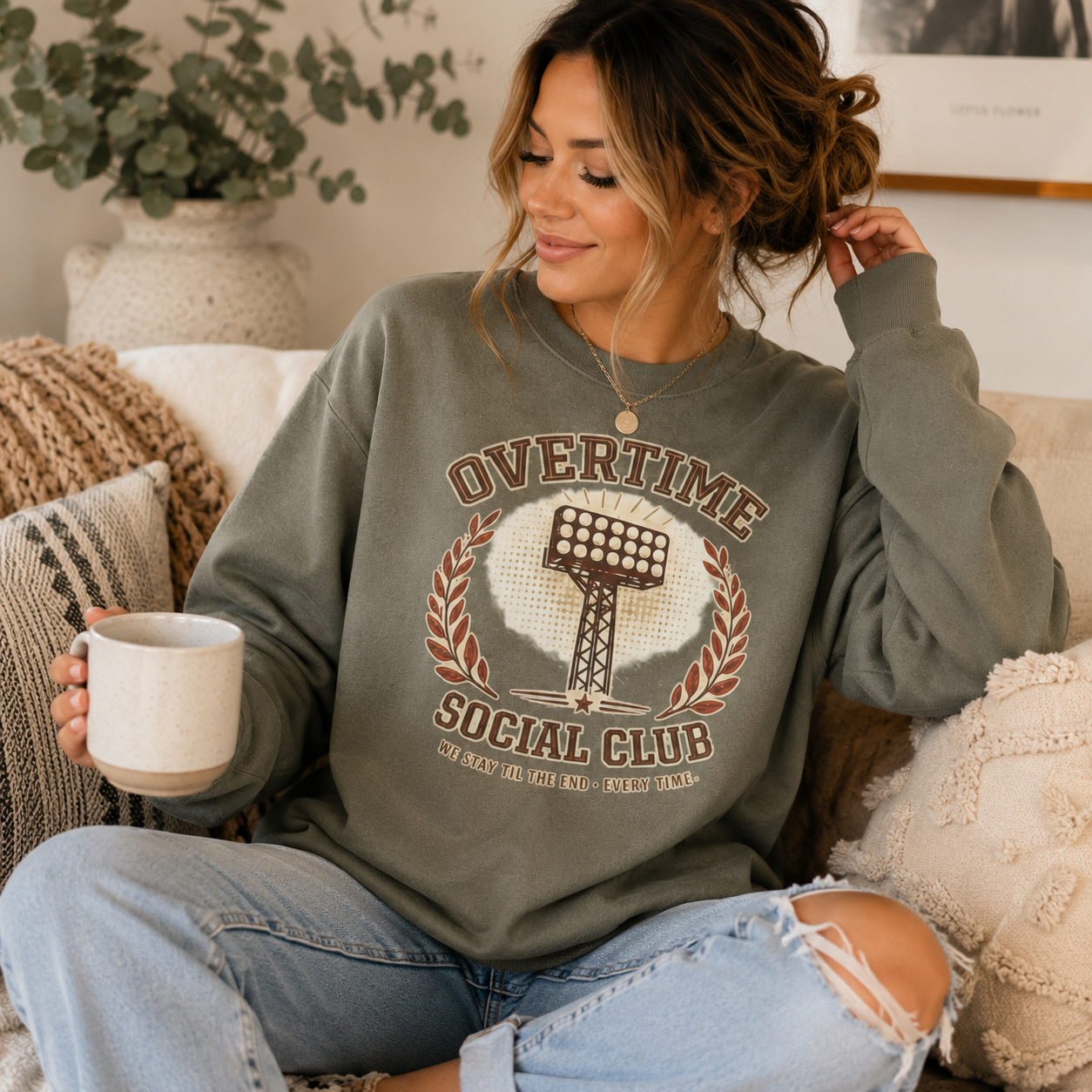 Tea Shirt Shoppe Wholesale olive crewneck sweatshirt with vintage stadium light graphic worn by a woman with a mug