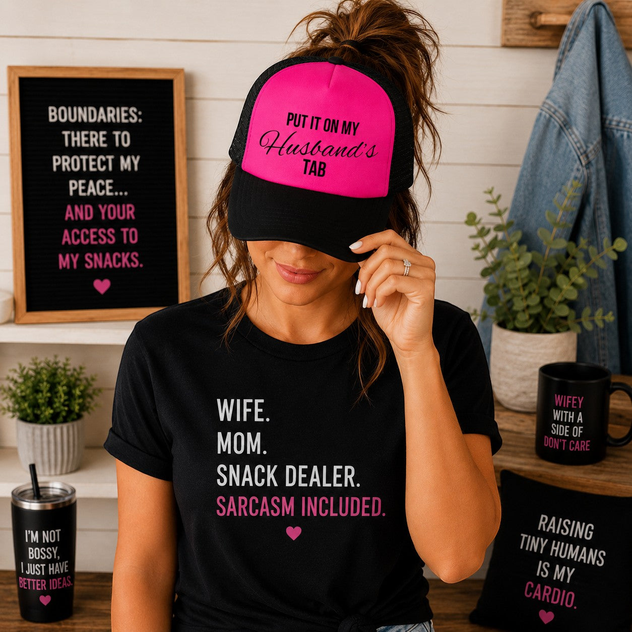 Tea Shirt Shoppe Wholesale neon pink and black foam trucker hat with Put It On My Husband's Tab graphic on a woman