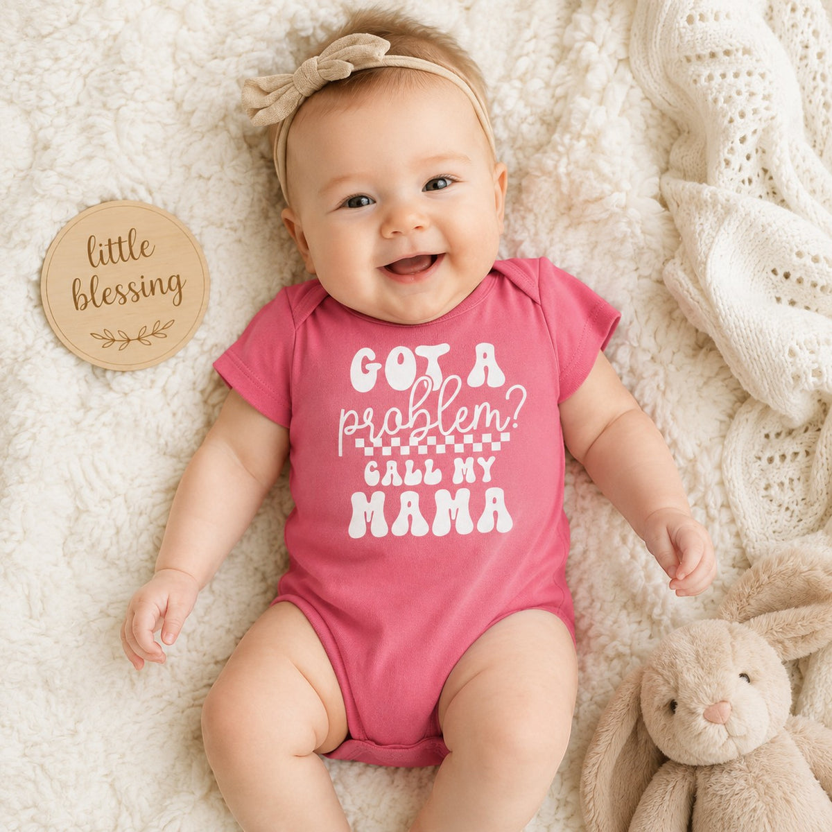 Tea Shirt Shoppe Wholesale pink infant bodysuit with Got a Problem Call My Mama text worn by a smiling baby