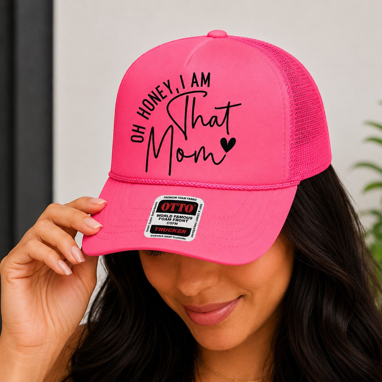 Tea Shirt Shoppe Wholesale bright pink trucker hat with "Oh Honey, I am That Mom" graphic and mesh back.
