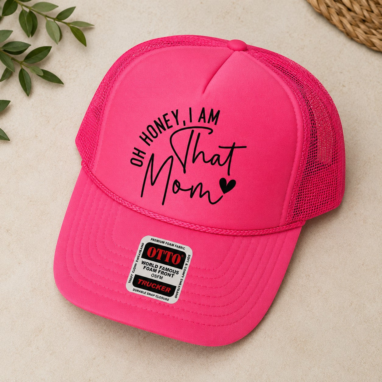 Tea Shirt Shoppe Wholesale bright pink trucker hat with "Oh Honey, I am That Mom" graphic and mesh back.