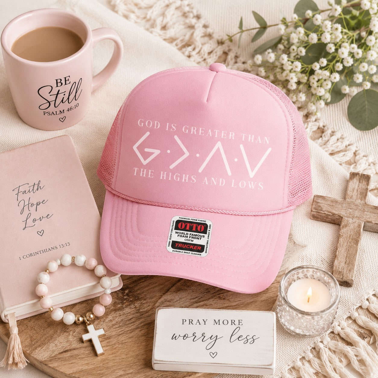 Tea Shirt Shoppe Wholesale pink trucker hat with "God Is Greater Than The Highs And Lows" graphic. Mesh back.