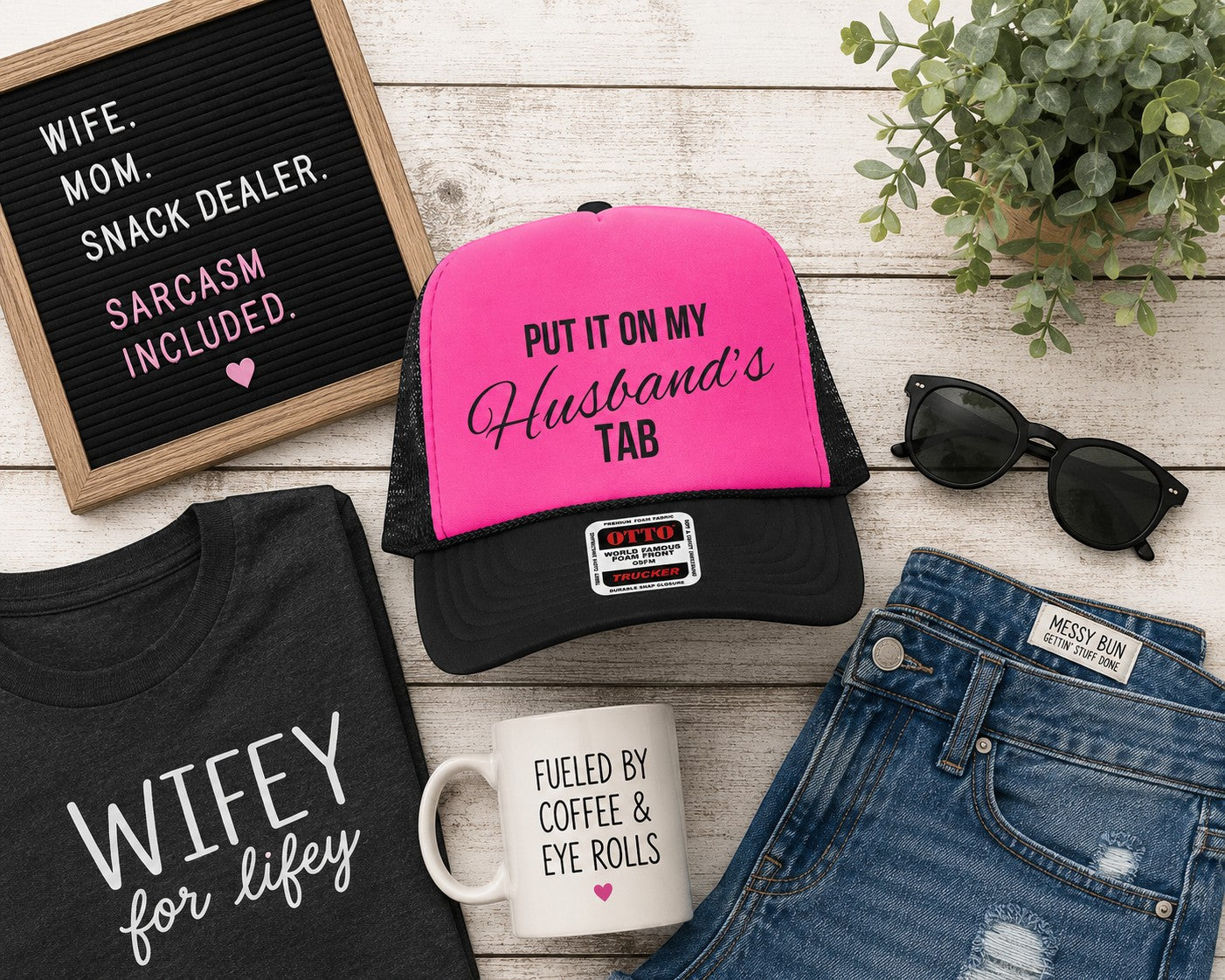 Tea Shirt Shoppe Wholesale neon pink and black trucker hat with Put It On My Husband's Tab text on a wooden surface.