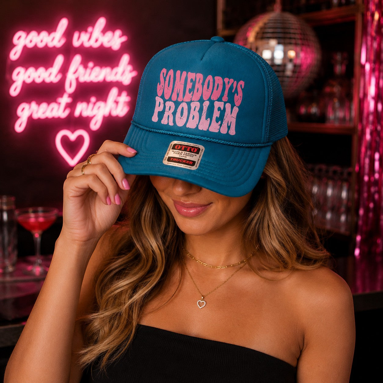 Tea Shirt Shoppe Wholesale teal trucker hat with pink Somebody's Problem graphic, foam front and mesh back.