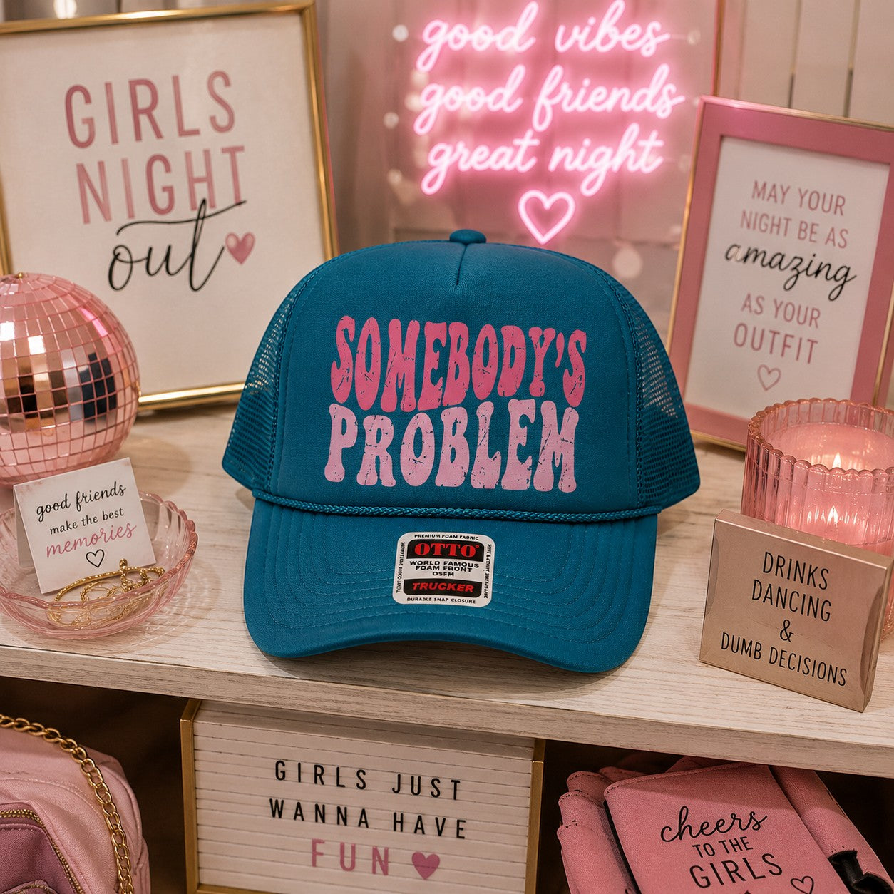 Tea Shirt Shoppe Wholesale teal trucker hat with pink distressed Somebody's Problem graphic and mesh back.