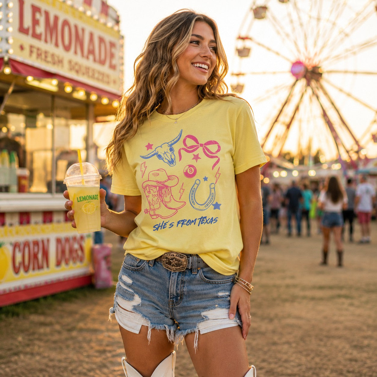 Tea Shirt Shoppe Wholesale yellow cotton graphic tee with western cowgirl motifs worn by a woman at a fair.