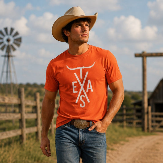Man wearing a burnt orange Tea Shirt Shoppe Wholesale Texas Longhorn graphic t-shirt, cowboy hat, and blue jeans.