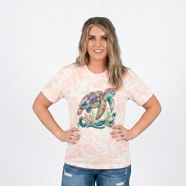 Tea Shirt Shoppe Wholesale peach tie dye 100% cotton t-shirt with a colorful sea turtle graphic and coral.